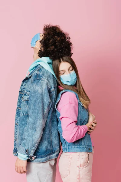 Teenager in medical mask standing near boyfriend on pink background — Stock Photo