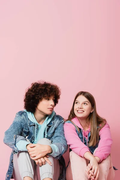 Curly adolescente olhando para a namorada sorridente no fundo rosa — Fotografia de Stock