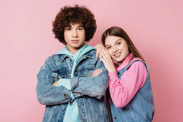 Smiling teenager hugging boyfriend with crossed arms isolated on pink — Stock Photo