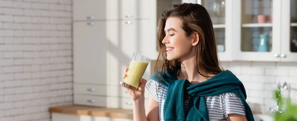 Jeune femme souriant tout en tenant un verre de jus frais, bannière — Photo de stock