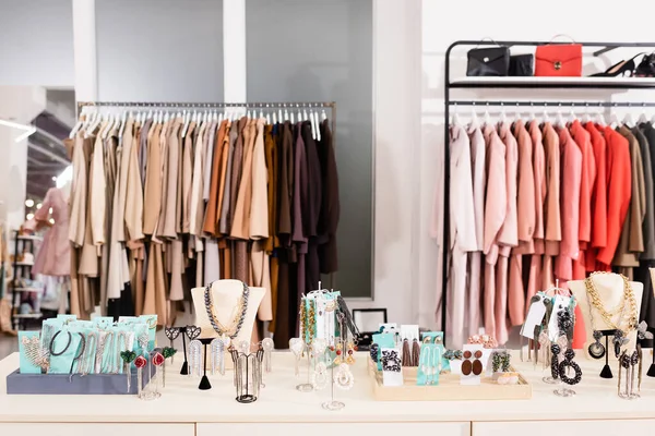 Аксессуары на столе в выставочном зале с одеждой на размытом фоне — стоковое фото