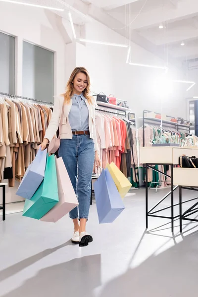 Jolie femme avec des sacs à provisions marchant dans le showroom — Photo de stock