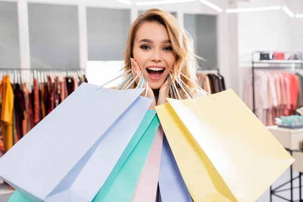Amazed woman with shopping bags looking at camera in showroom — Stock Photo