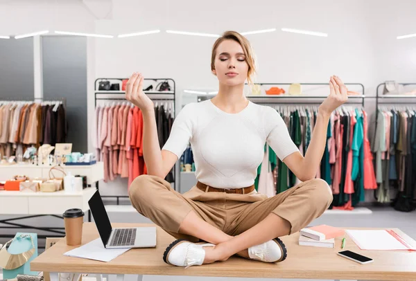 Verkäufer meditiert in der Nähe von Geräten auf dem Tisch im Showroom — Stockfoto