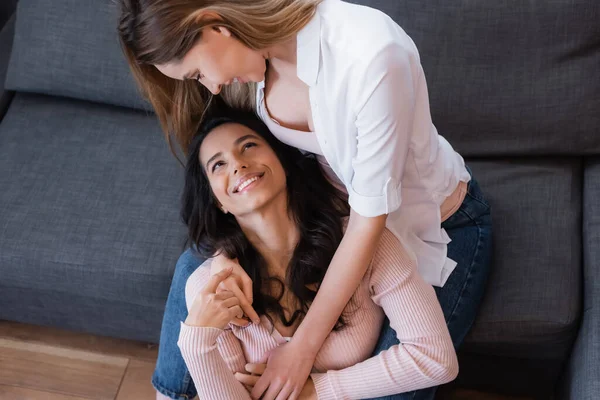 Cheerful lesbians hugging and looking at each other in living room — Stock Photo