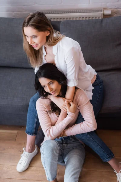 High angle view of cheerful lesbians hugging near sofa in living room — Stock Photo