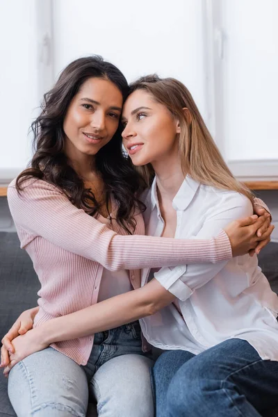 Novias felices en ropa casual abrazándose en la sala de estar - foto de stock