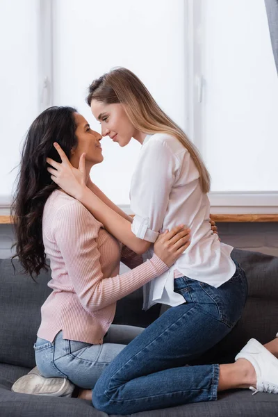 Vista laterale delle lesbiche felici che si abbracciano in soggiorno — Foto stock