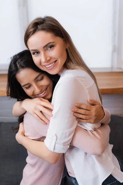 Glückliche Freundinnen, die zu Hause lächeln und sich umarmen — Stockfoto