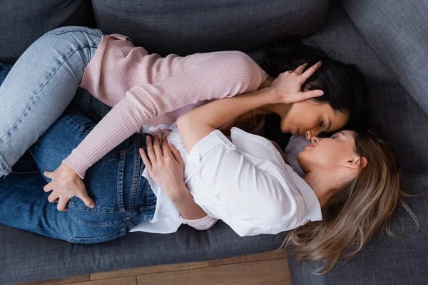 Vista superior de namoradas abraçando enquanto deitado no sofá na sala de estar — Fotografia de Stock