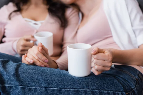Abgeschnittene Ansicht von Freundinnen mit Tassen Tee im Wohnzimmer — Stockfoto