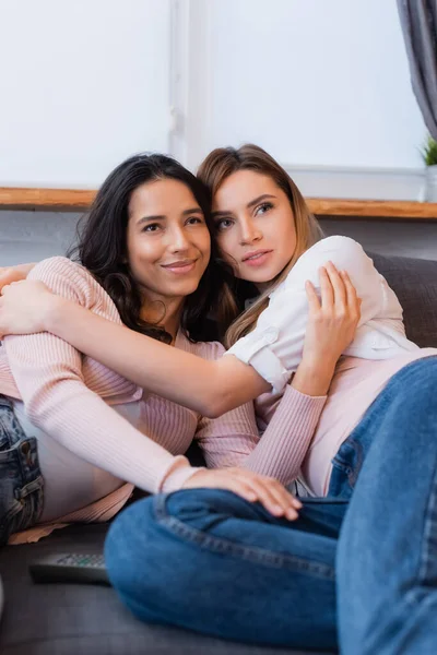 Glückliche und hübsche Freundinnen, die sich auf der Couch umarmen und chillen — Stockfoto