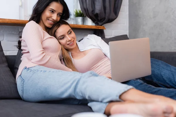 Happy lesbian couple watching movie on blurred laptop — Stock Photo