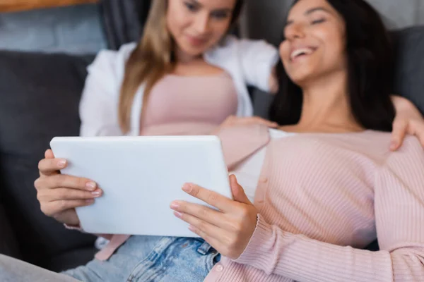 Verschwommenes und glückliches lesbisches Paar schaut sich Film auf digitalem Tablet zu Hause an — Stockfoto