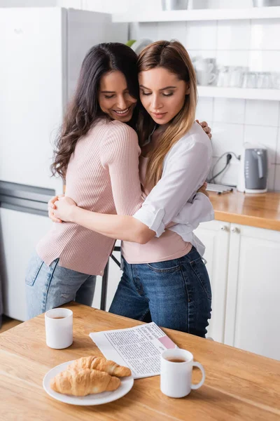 Happy girlfriends hugging near breakfast on table — Photo de stock