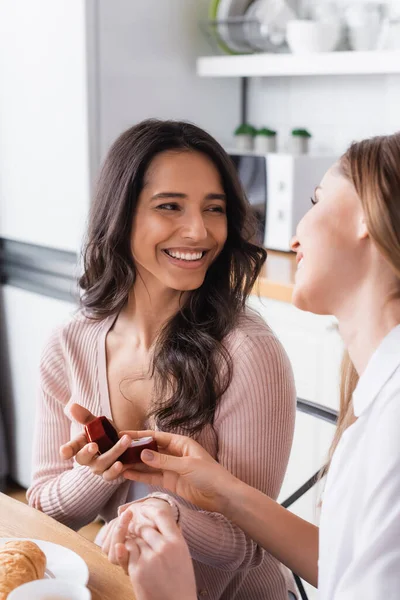 Glückliche Freundinnen, die einander anschauen und Ehering in der Hand halten, Heiratsantrag-Konzept — Stockfoto