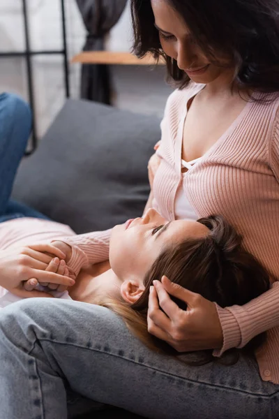 Lesbische Frau liegt auf Knien von lächelnder Freundin im Wohnzimmer — Stockfoto