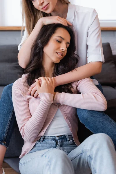 Happy lesbian couple embracing each other near sofa in living room — Stock Photo