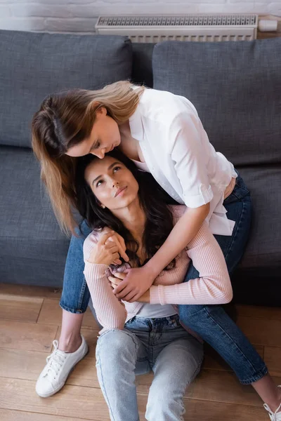 Hochwinkelaufnahme von lesbischem Paar, das sich im Wohnzimmer umarmt — Stockfoto