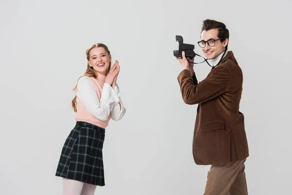 Mujer feliz en ropa retro posando cerca de hombre con cámara vintage aislado en gris — Stock Photo