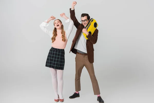 Homem alegre segurando boombox vintage enquanto dança com mulher animada no cinza — Fotografia de Stock