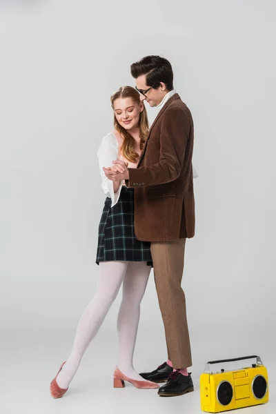 Full length view of couple in retro outfit dancing near vintage tape recorder on grey — Stock Photo