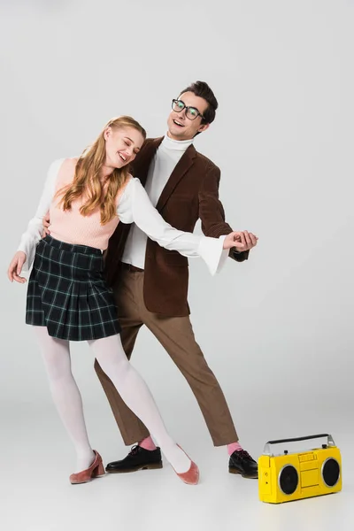 Couple heureux en tenue rétro dansant près de boombox vintage sur gris — Photo de stock