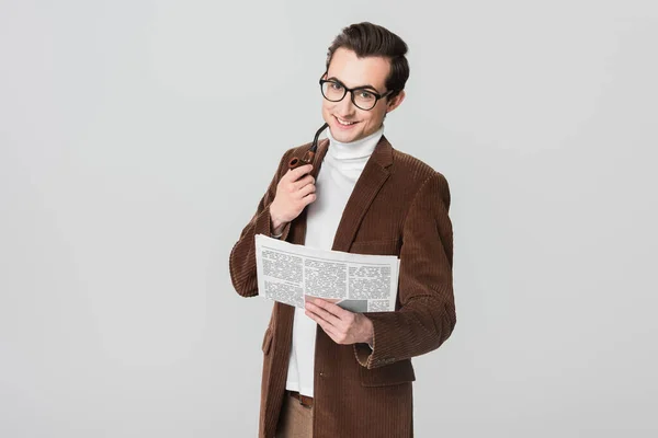 Joyful man with newspaper and smoking pipe looking at camera isolated on grey — Stock Photo