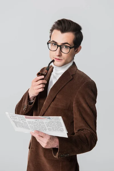 Young man in velvet blazer holding smoking pipe and newspaper isolated on grey — Stock Photo