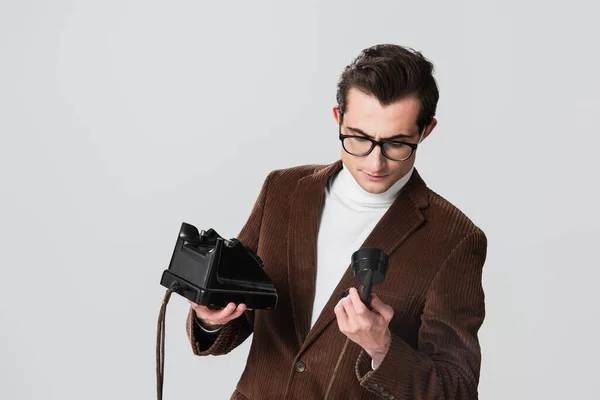Vecchio stile uomo in velluto blazer guardando cuffie del telefono vintage isolato su grigio — Foto stock