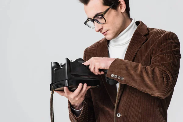 Junger Mann mit Brille wählt Nummer auf Oldtimer-Telefon isoliert auf grau — Stockfoto