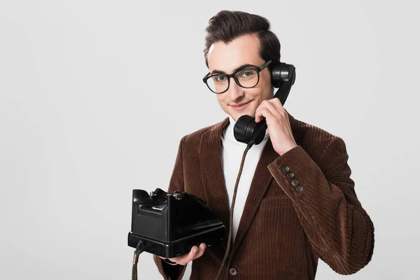 Uomo sorridente con occhiali e blazer di velluto che parla su telefono vintage isolato su grigio — Foto stock