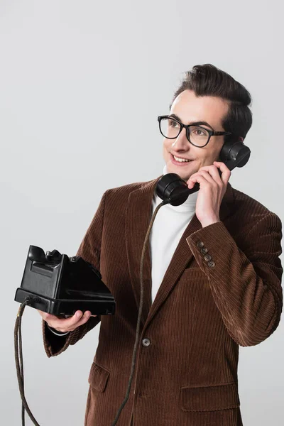 Glücklicher Mann im Samtblazer, der wegschaut, während er am Telefon telefoniert, isoliert auf grau — Stockfoto