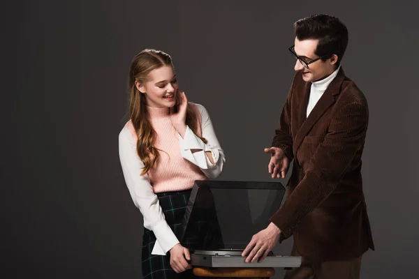 Smiling man pointing at record player near pleased woman isolated on black — Stock Photo