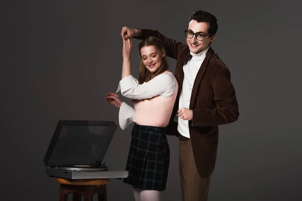 Happy, old fashioned couple dancing near record player isolated on black — Stock Photo
