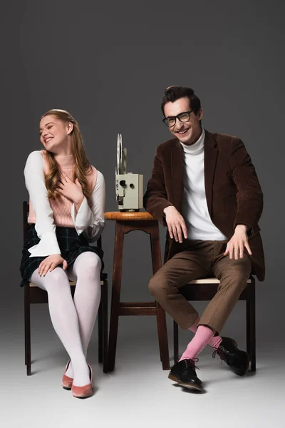 Rindo casal assistindo comédia no projetor de filme em fundo cinza — Fotografia de Stock