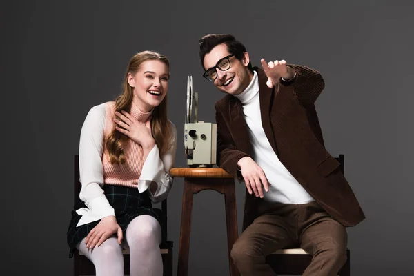 Смеющийся мужчина показывает пальцем, глядя на комедию рядом с женщиной, изолированной от черного — стоковое фото