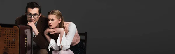 Worried woman watching tv near concentrated man isolated on black, banner — Stock Photo