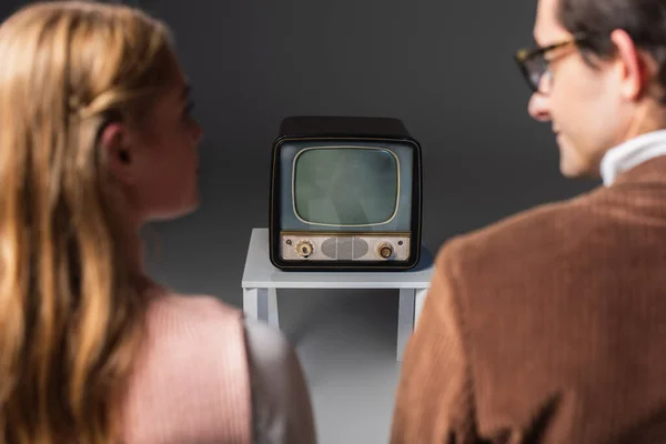 Vista posteriore di coppia offuscata guardando tv vintage su grigio — Foto stock