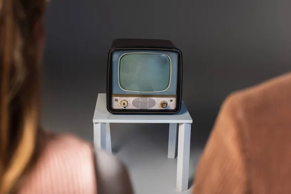 Vue recadrée du couple flou près de la télévision vintage sur fond gris — Photo de stock