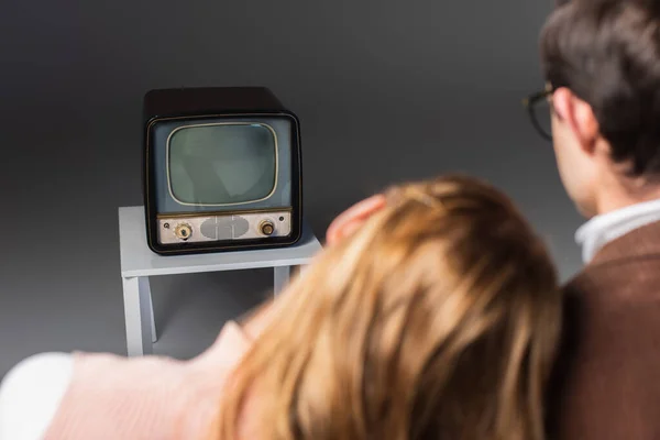 Back view of blurred man and woman watching retro tv on grey background — Stock Photo
