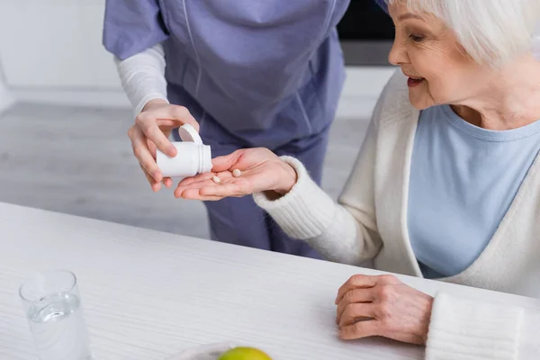 Travailleur social donnant des médicaments à une femme âgée — Photo de stock
