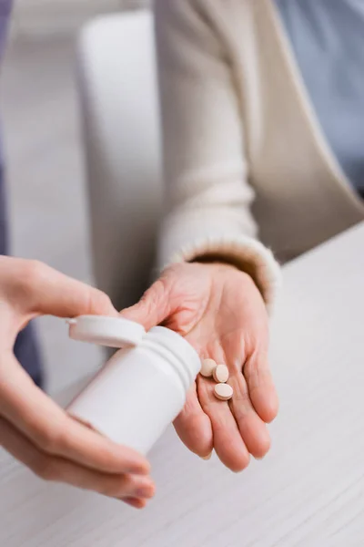 Cropped view of social worker giving medication to elderly woman — Stock Photo