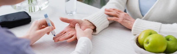 Visión parcial de la trabajadora social inyectando insulina a una mujer diabética anciana, pancarta - foto de stock