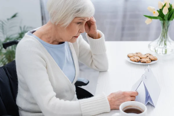 Seniorin, die unter Gedächtnisverlust leidet, schaut zu Hause auf Kalender — Stockfoto