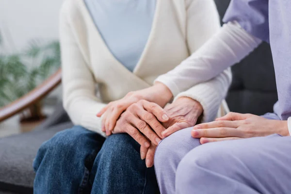 Vista recortada de la enfermera tocando la mano de la mujer anciana en casa - foto de stock