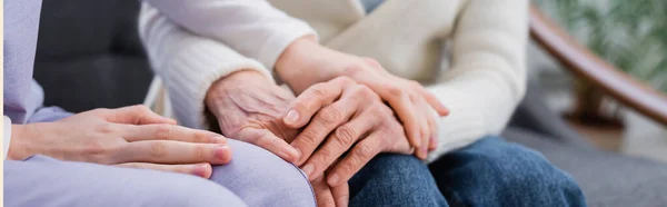 Partial view of young social worker touching hand of aged woman, banner — Stock Photo