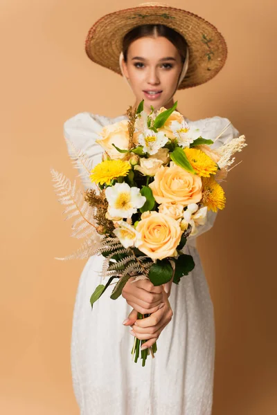 Blurred woman in dress holding bouquet of flowers on beige — Stock Photo