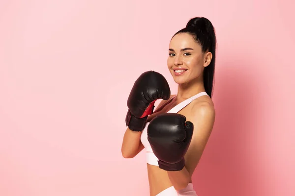 Donna allegra in abbigliamento sportivo e guanti da boxe su rosa — Foto stock