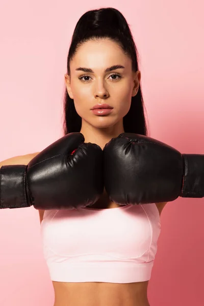 Femme forte en vêtements de sport et gants de boxe regardant la caméra sur rose — Photo de stock